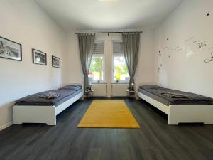 a bedroom with two beds and a yellow rug at Herne Zentral Apartment in Herne