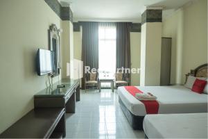 a hotel room with two beds and a television at Akur Hotel Malioboro Mitra RedDoorz in Yogyakarta