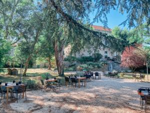 un groupe de tables et de chaises devant un bâtiment dans l'établissement Hotel Savel, à Ruoms