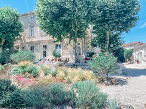 un giardino di fronte a un edificio con alberi e fiori di Hotel Savel a Ruoms