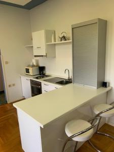 uma cozinha com um balcão branco e duas cadeiras em Apartman Villa Klein em Opatija