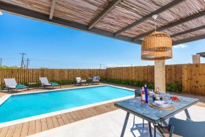 a swimming pool in a backyard with a table and chairs at Villa Maira Azalea by Villa Plus in Katastárion +9 photos