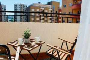 My Home in Prishtina - Spacious & Cozy 2BR Apartment with Balcony في بريشتيني: طاولة وكراسي على شرفة مطلة على مباني