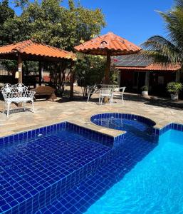 a swimming pool with chairs and a table and an umbrella at Pousada Encanto dos Anjos in Pirenópolis