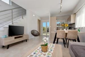ein Wohnzimmer mit einem TV und einem Tisch mit Stühlen in der Unterkunft Villa Vilenia Horizon by Villa Plus in Katastárion