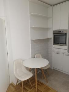 a white kitchen with a table and two chairs at Jednosoban stan Zoja in Podgorica