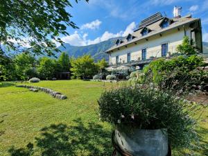 una gran casa blanca con un patio con flores en Boutique Hotel Dobra Vila Bovec, en Bovec