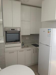 La cuisine est équipée de placards blancs et d'un réfrigérateur blanc. dans l'établissement Jednosoban stan Zoja, à Podgorica