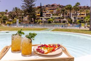 stół z talerzem owoców i napojów przy basenie w obiekcie Increible Terraza con vistas al mar en San Agustín (3 hab) w mieście San Agustin
