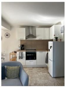 uma cozinha com armários brancos e um frigorífico em Appartement duplex plein sud sur le port de Bonifacio em Bonifacio