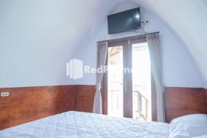 a bedroom with a bed and a tv on the wall at Baron Hill Resort Gunung Kidul Mitra RedDoorz in Baron
