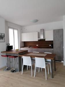 eine Küche mit einem Holztisch und weißen Stühlen in der Unterkunft Casa vacanze Sissi in Arco