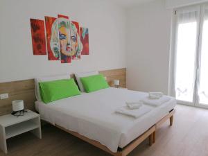 a bedroom with a large white bed with green pillows at Casa vacanze Sissi in Arco