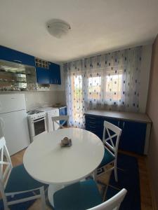 una pequeña cocina con mesa blanca y sillas en Apartman “IVA”, en Drvar