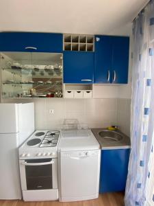 cocina con armarios azules, fogones y fregadero en Apartman “IVA”, en Drvar