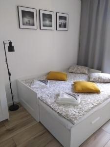 a white bed with yellow pillows on top of it at Apartament Rodzinny Baltic Park Stegna in Stegna