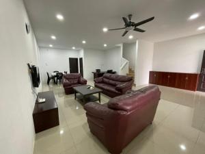 a living room with leather furniture and a ceiling fan at Wawasan Sweet Home - UTS Sibu in Sibu