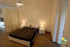 a bedroom with a bed with two night stands and a chandelier at M.H Bovio Apartment in Follonica