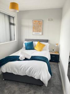 a bedroom with a large bed with blue and yellow pillows at HILLTOP PLACE Suites Near Doncaster RaceCourse in Doncaster