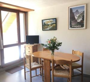 a dining room table with a vase of flowers on it at Studio St Lary proche du centre, au calme avec vue montagne in Saint-Lary-Soulan