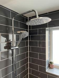 a shower in a bathroom with black tiles at Location-Comfortable Beds-Free Parking-Families in Nottingham