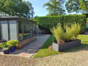 um jardim com um gazebo e algumas plantas em The Annexe @Granny’s Apple Lodge em Blakeney