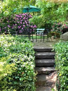 a stone path with chairs and an umbrella in a garden at Frederick William House in Falmouth