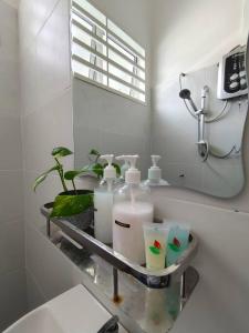 a bathroom with a shelf with toiletries and a mirror at RUMAH AINA Homestay Bukit Changgang Private Pool in Kampong Melot