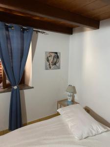 a bedroom with a bed with a blue curtain at La Casetta di Ninetta in Ustica