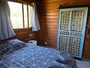 Un dormitorio con una cama azul y una ventana en Le Chalet de la Dordogne, en Mauzac-et-Grand-Castang