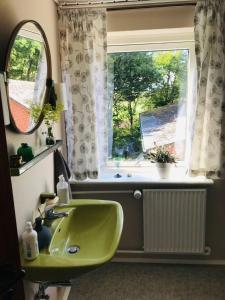 La salle de bains est pourvue d'un lavabo vert et d'une fenêtre. dans l'établissement B & B Mølgaard by Skjern, à Skjern