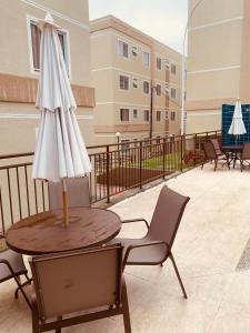 einen Tisch mit Sonnenschirm und Stühlen auf dem Balkon in der Unterkunft Parque Caminho das Baraúnas in Caruaru