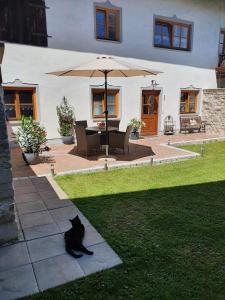 a black cat sitting on a sidewalk under an umbrella at Ferienwohnung Bärnham in Babensham