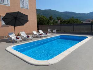 una piscina con sedie e ombrellone accanto a un edificio di Apartments Ukic - with large outdoor pool a Kaštela (Castelli)