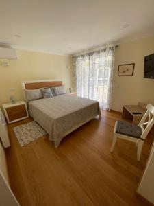 a bedroom with a bed and a chair and a window at Alvor mountain view villa with private pool in Alvor