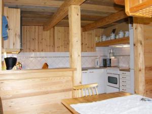 a kitchen with wooden walls and a table and a stove at 8 person holiday home in VIMMERBY in Rumskulla