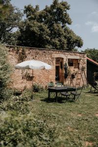 uma mesa com um guarda-chuva em frente a um edifício de tijolos em Maison d'hôtes Bel Estiu em Saint-Geniès