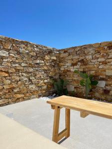 una panca di legno seduta di fronte a un muro di pietra di Kastro Antiparos a Città di Antiparo