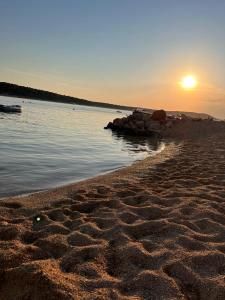 a sunset on a beach with rocks in the water at Sunny view Apartman in Barbat na Rabu