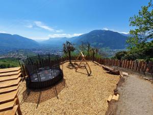 a playground with a swing and a wooden fence at Residence Innerfarmerhof in Tirolo