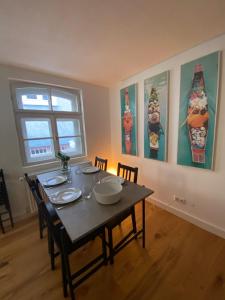 a dining room with a table with chairs and paintings at SCHLOSS & ALTSTADT - Modern & Stylish für 6 Küche in Dachau