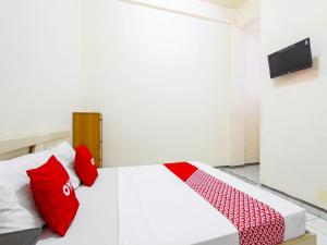 a bedroom with a bed with red pillows on it at OYO 91354 Hotel Mutiara in Magelang