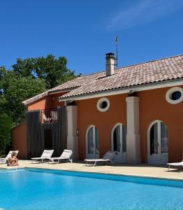 a house with a swimming pool and two lawn chairs at La Petite Aiguebonne in Allex