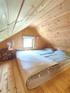 a bed in a log cabin with a window at Self Check-in Sauna Cabin next to Hiking Trails in Kärde