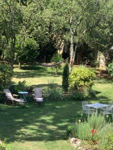 un patio con sillas y una hamaca en el césped en L'adresse à Besançon en Besançon