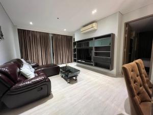 a living room with a leather couch and a large tv at Veranda Residences Pattaya By Phung in Jomtien Beach