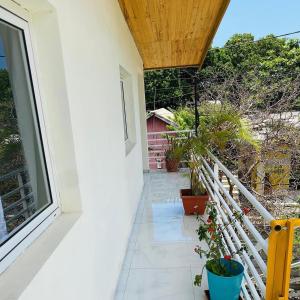 einen Balkon eines Hauses mit Pflanzen und einem Fenster in der Unterkunft La Vue De Haut- T3 avec vue imprenable sur la mer in Bouéni
