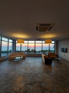 ein großes Wohnzimmer mit Sofas, Tischen und Fenstern in der Unterkunft Aeolos Hotel in Kamariotissa