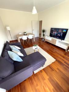 ein Wohnzimmer mit einem schwarzen Sofa und einem TV in der Unterkunft Cozy apartment with Free Parking & close to Lake in Lugano