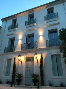 - un bâtiment blanc avec une porte et un balcon dans l'établissement LAZARE Maison de Maître , appartements de standing avec parking privatif à seulement 7 minutes à pied du centre historique de Béziers, à Béziers